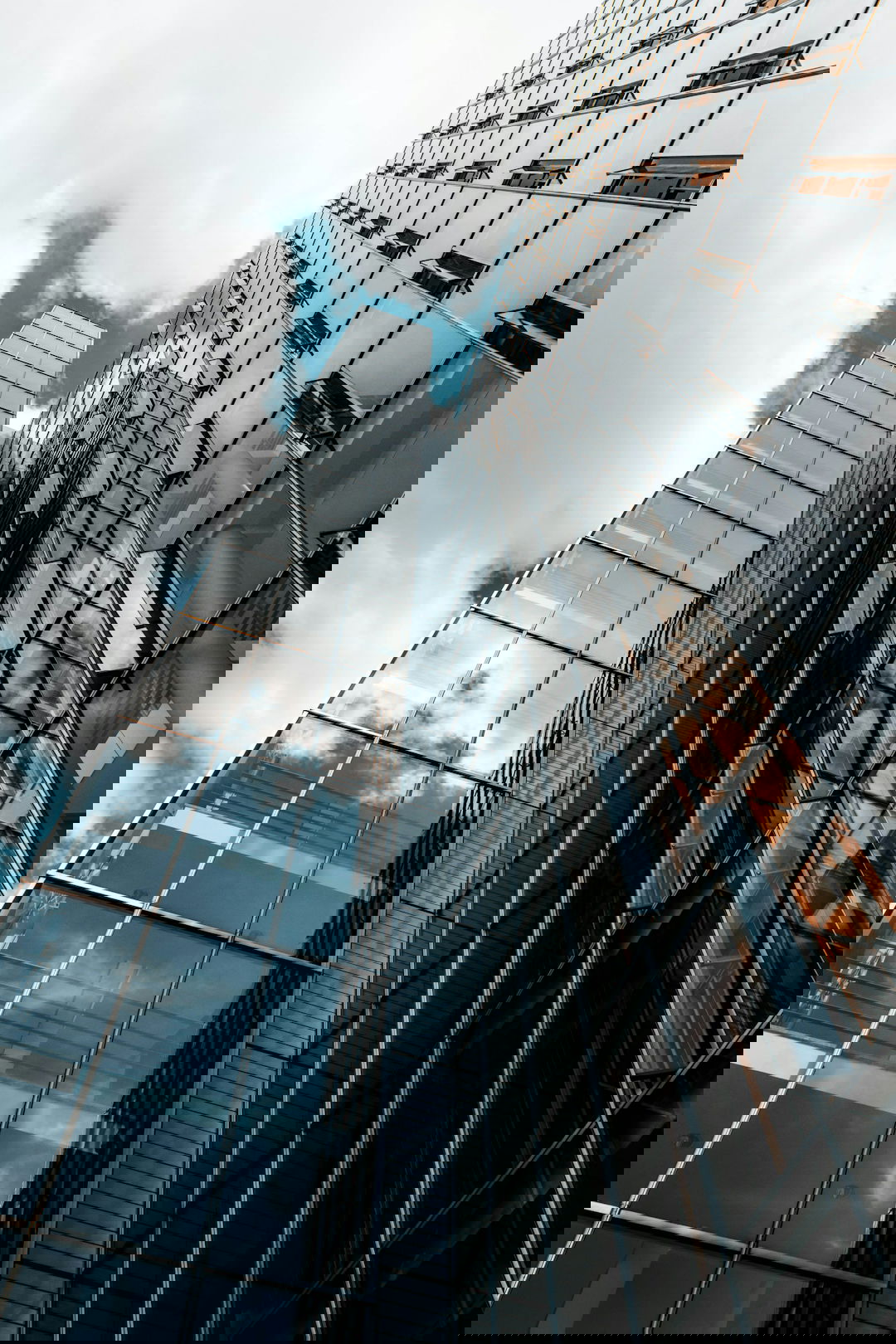 low angle photography of glass building under cloudy sky